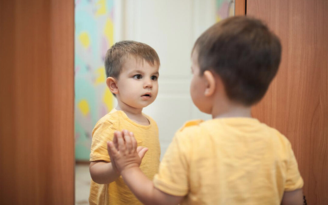 A Young child sees himself in a mirror